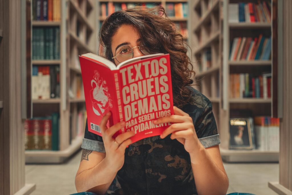 A young woman reading a book in a cozy library setting in Brazil.