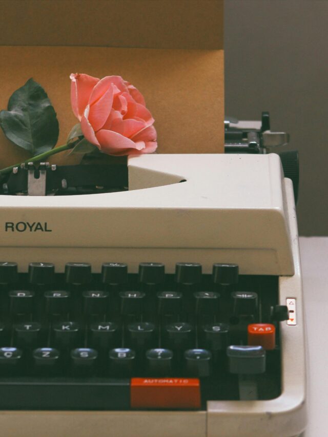 A vintage typewriter holds a pink rose and a letter, evoking nostalgia and romance.
